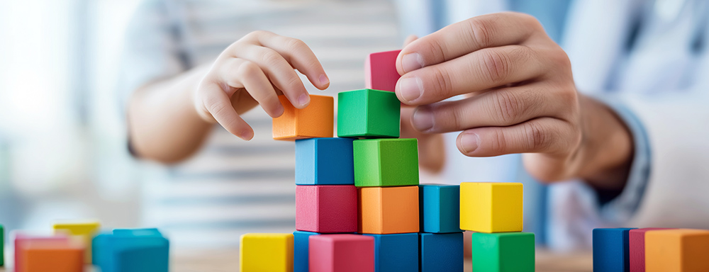 Arzt hilft einem Jungen bunte Bauklötze zu stapeln